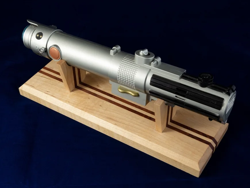A maple lightsaber hilt stand with a purpleheart inlay