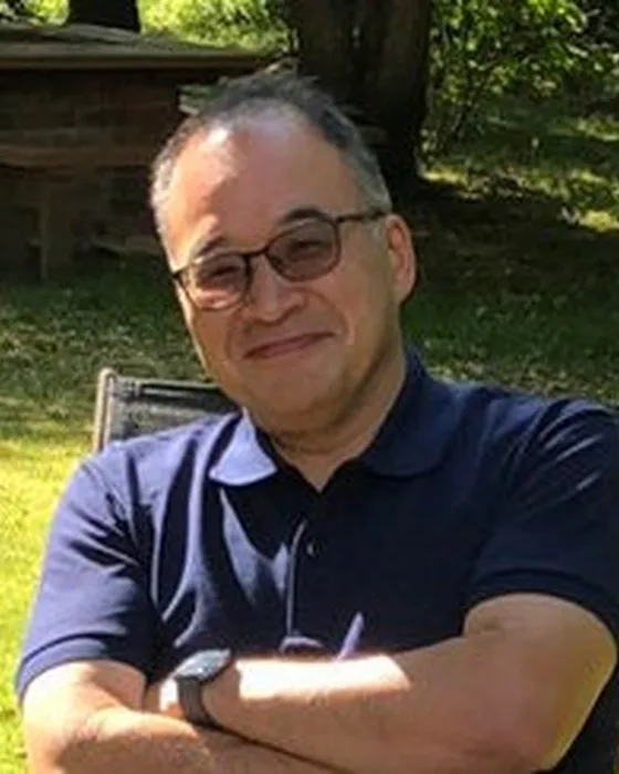 Ken Murayama, the owner and woodworker behind Murayama Woodworks, outdoors in a navy polo
